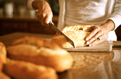 Woman slicing bread Rediscovering Bread - EAT LOVE SAVOR International Luxury Lifestyle Magazine